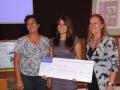 Vista de grupo de la Vicerrectora de Cultura y Deporte, la Directora de la Biblioteca Universitaria y la ganadora del primer premio, quien sostiene un cartel-cheque