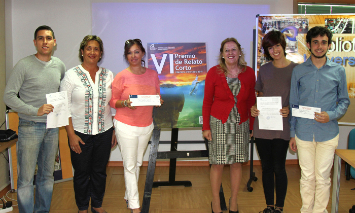 Seis personas posan a un lado y otro del cartel del evento; cuatro premiadas portan certificados o cheques, acompañadas de la directora de la Biblioteca Universitaria y de la Vicerrectora de Internacionalización y Cooperación.