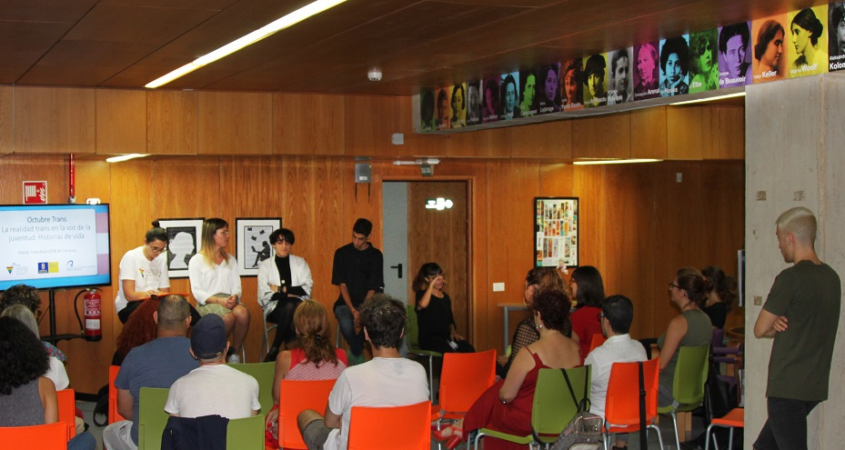 Vista de una mesa redonda con público en una zona de la biblioteca