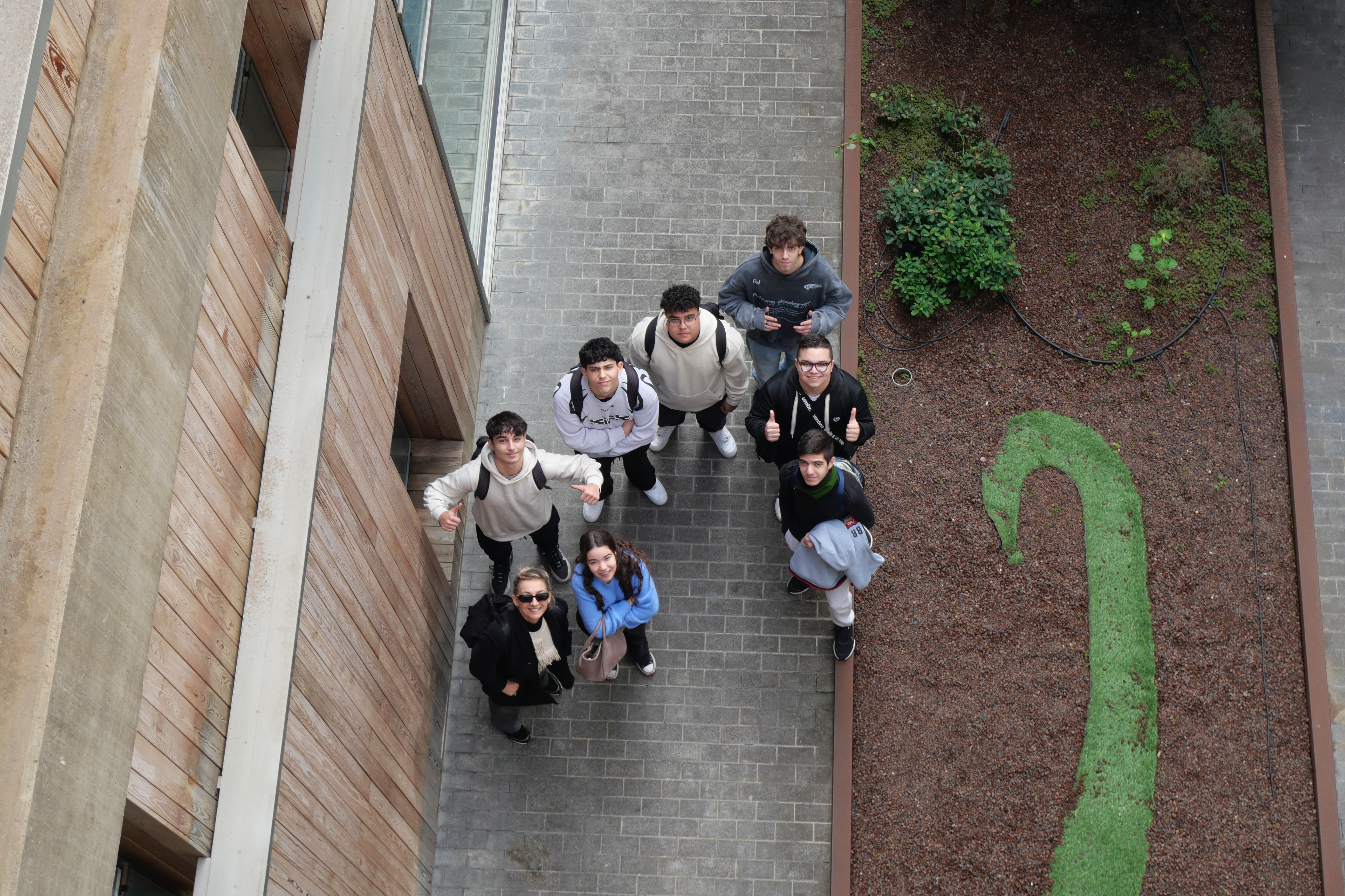 Vista cenital de estudiantes en un patio mirando hacia arriba.