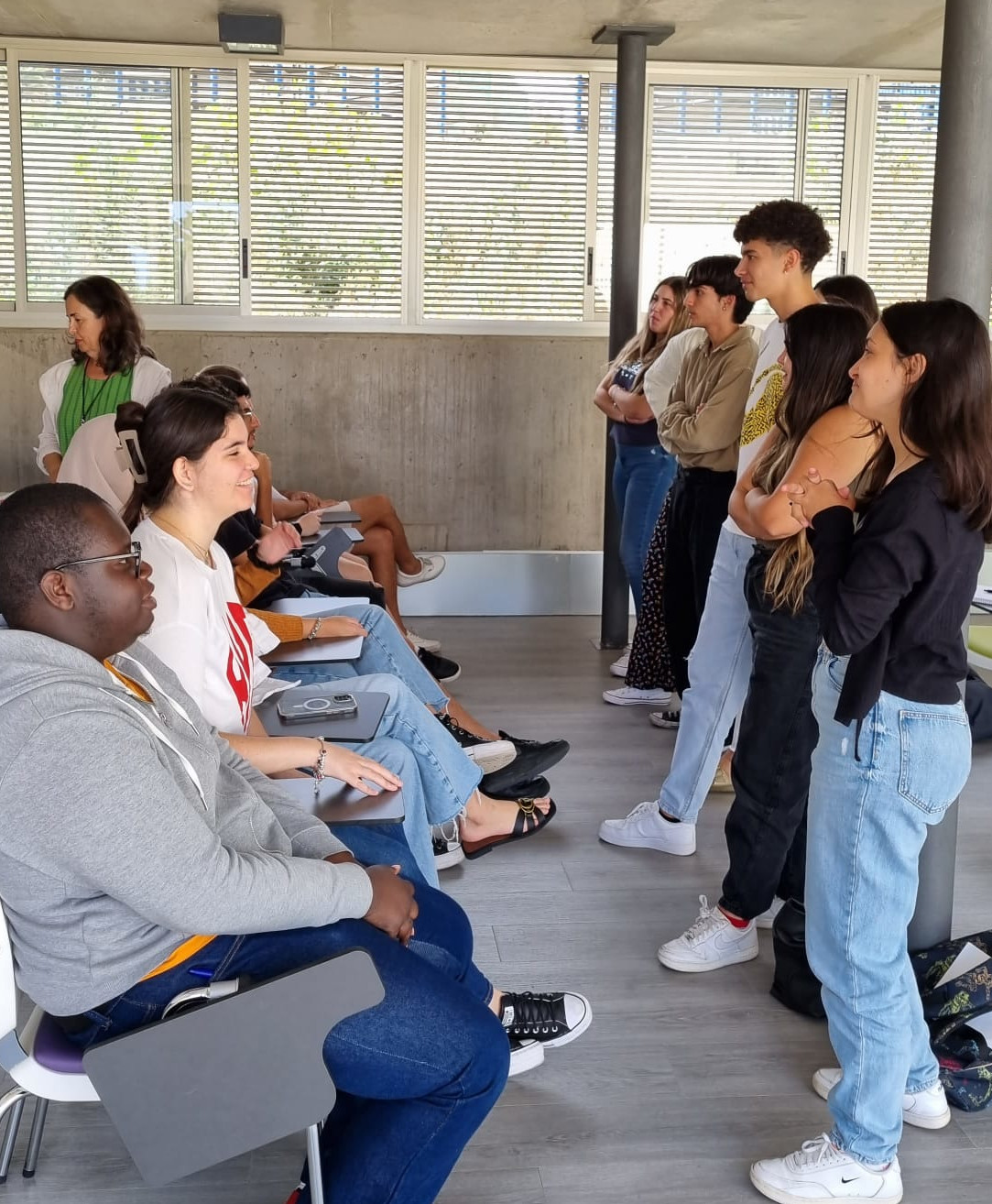 Un grupo de estudiantes se alinea de pie frente a otro grupo sentado.