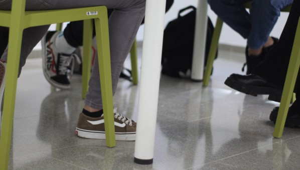 Patas de las sillas en las que hay 3 estudiantes sentados