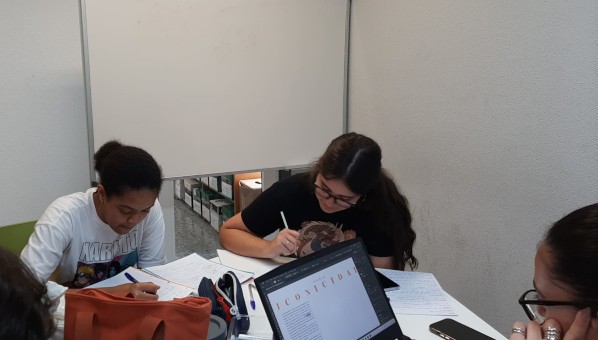Mesa 3 4 estudiantes en torno a una mesa de estudio, frente a una pizarra blanca.